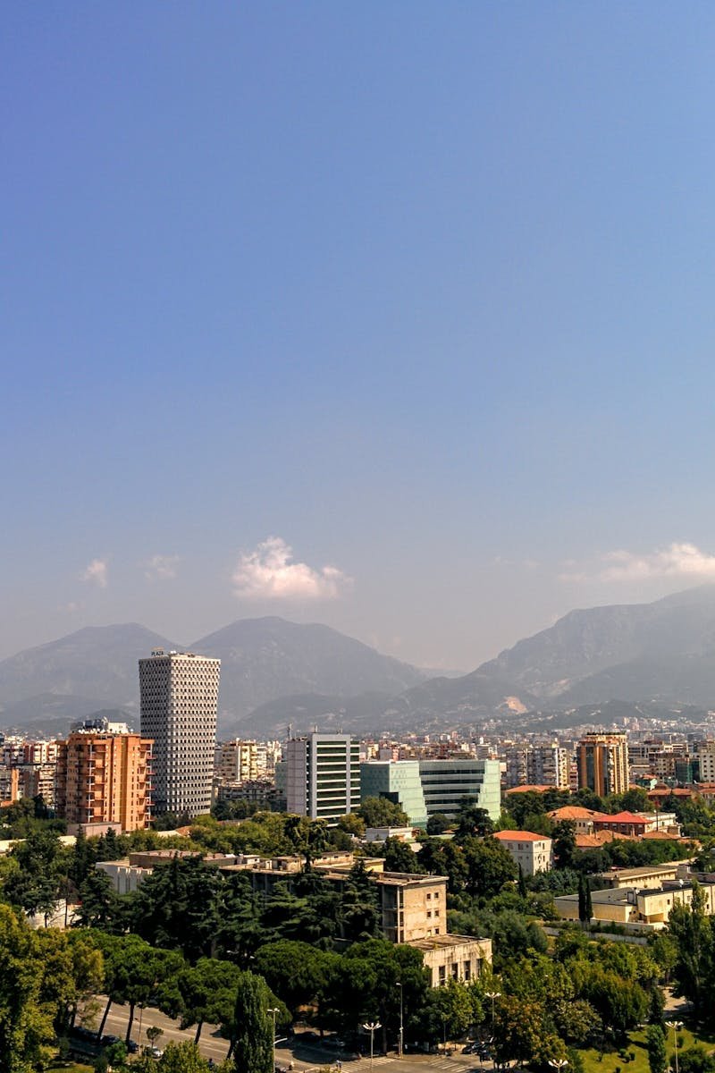Aerial view of Tirana, Albania's capital, with mountain backdrop and clear skies.