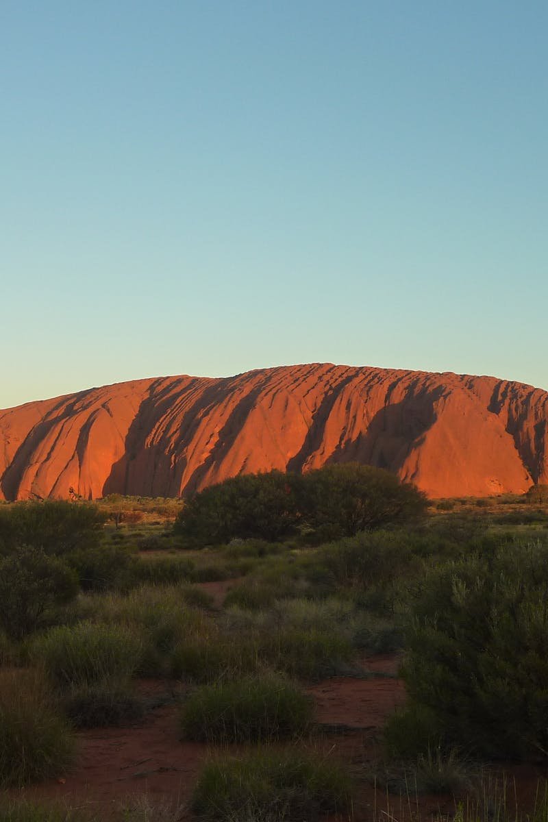 Capture the majestic Uluru rock formation glowing under the sunset. A natural wonder in Australia's Outback.