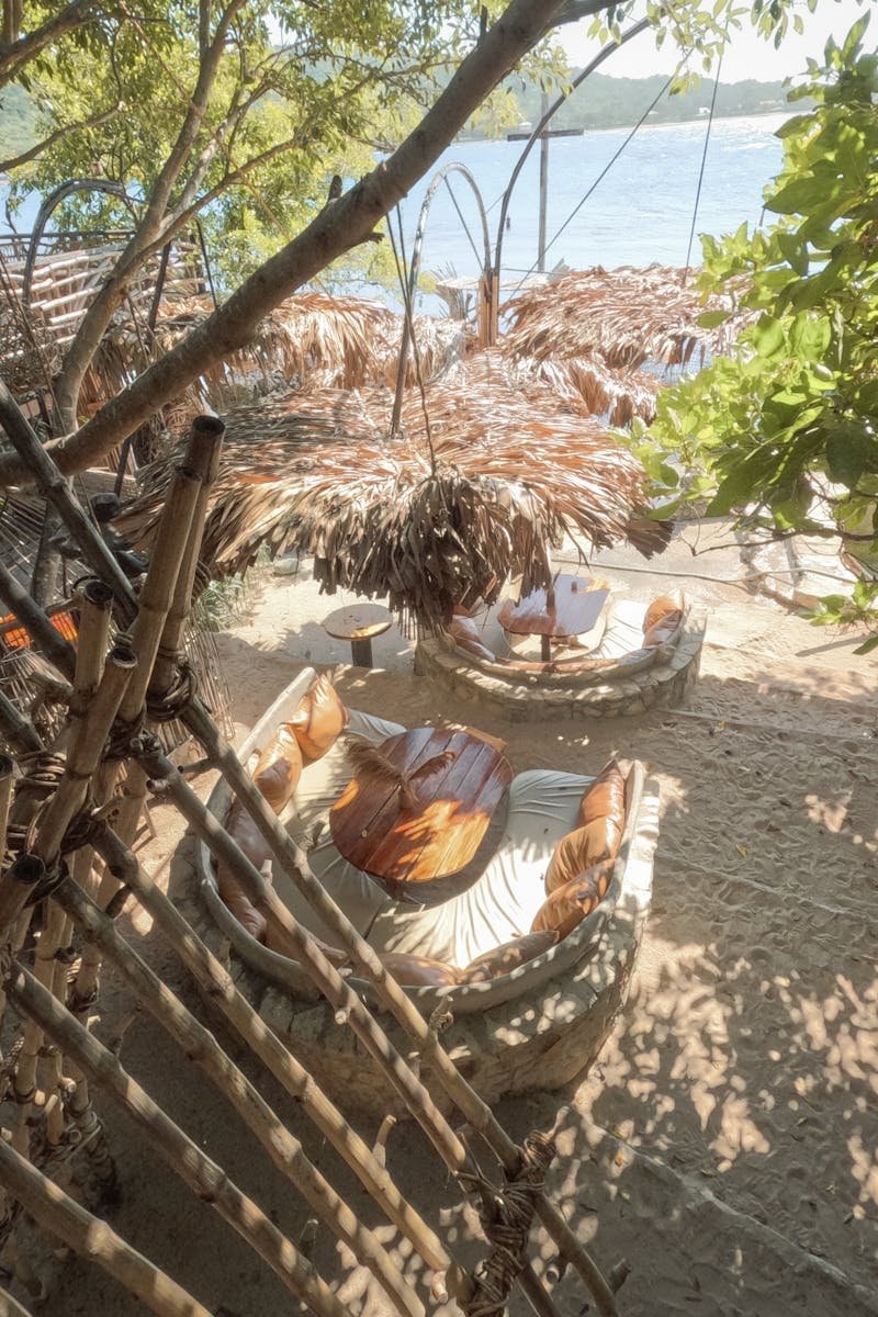 Tranquil bamboo seating area under palm shades on Santiago's tropical beach.