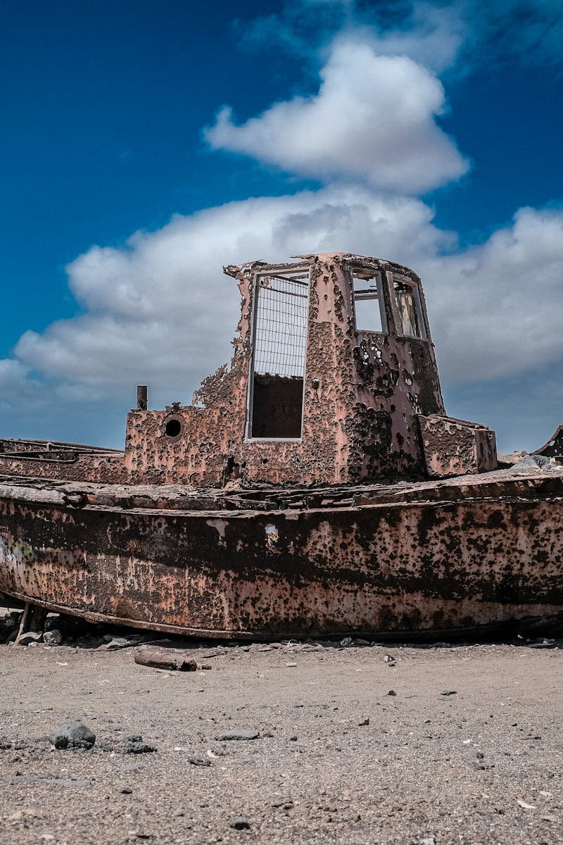 An abandoned rusty boat on the sandy shores of Pedra Lume, Sal Island, under a vivid blue sky.