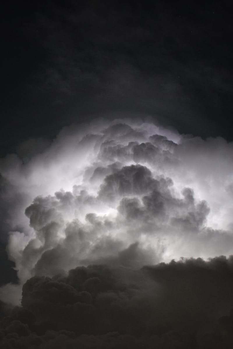 Powerful lightning illuminates dark storm clouds at night, creating a dramatic and mysterious sky.