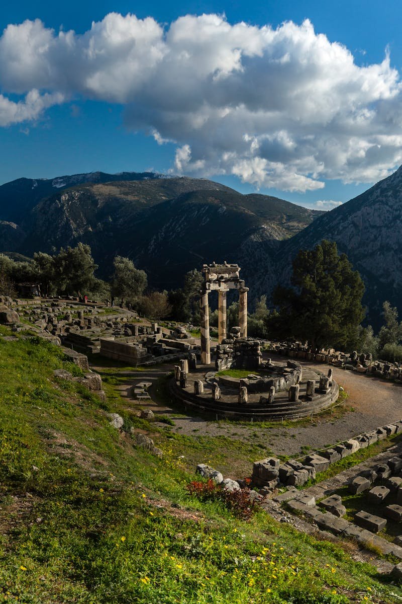 Explore the ancient ruins of Delphi, Greece, set against a stunning mountain landscape under a vibrant blue sky.