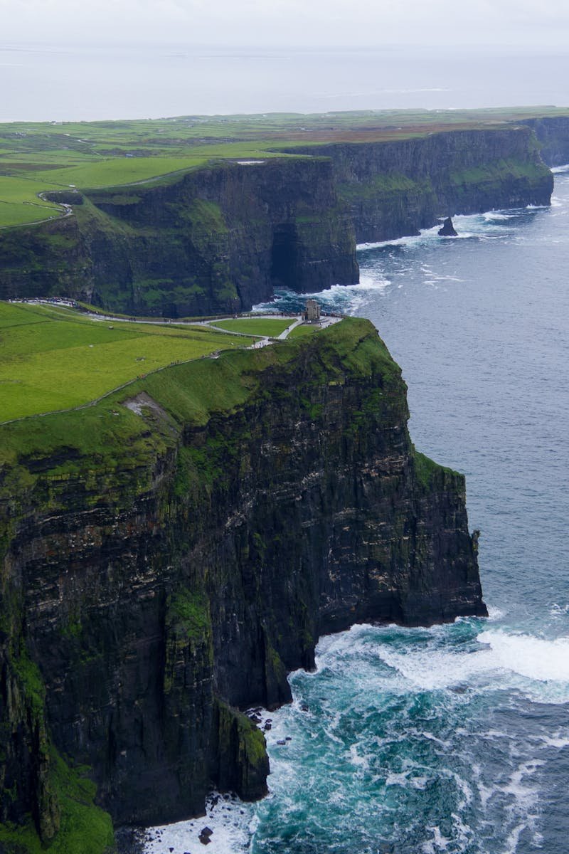 Stunning aerial view of the Cliffs of Moher, County Clare, Ireland with lush green landscapes and ocean waves.