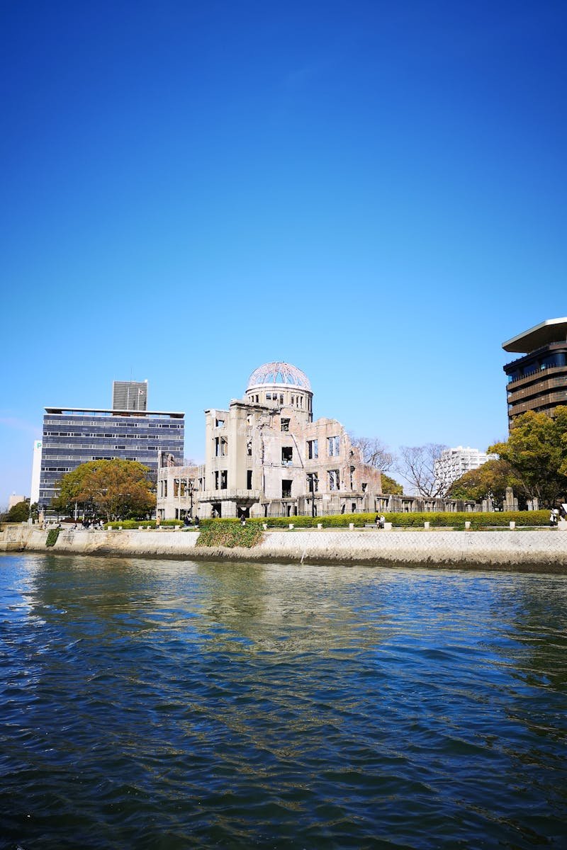 View of the iconic Hiroshima Peace Memorial with clear blue skies, reflecting on the water.