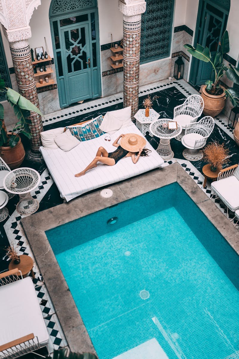 Elegant indoor pool with a woman lounging, set within a Moroccan riad in Marrakesh.