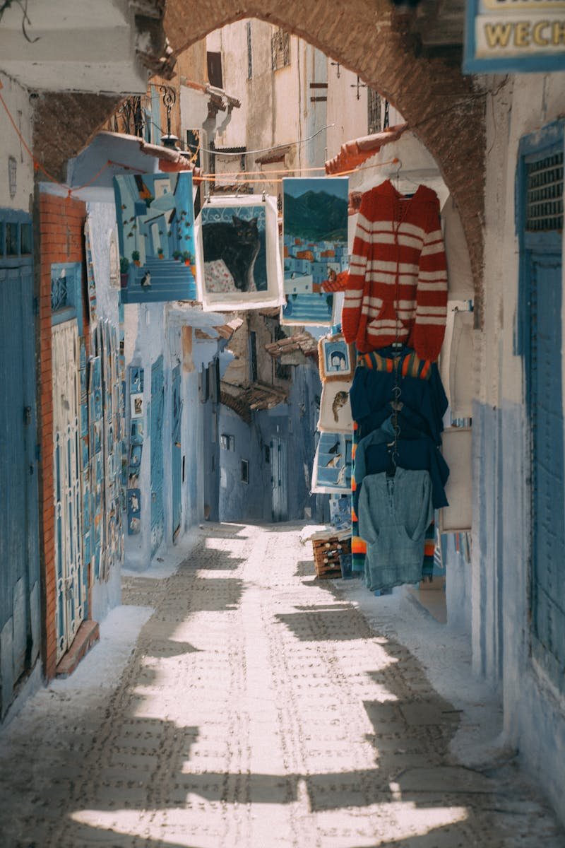 Explore the vibrant blue streets of Chefchaouen, Morocco, adorned with colorful textiles and art.