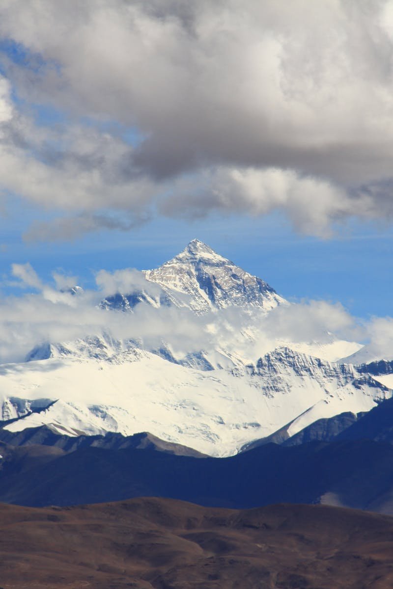 Beautiful snow-covered mountain peaks under fluffy clouds, showcasing nature's grandeur.