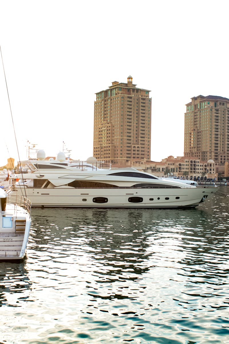 Scenic view of yachts docked at Doha marina with striking skyscrapers at sunset.