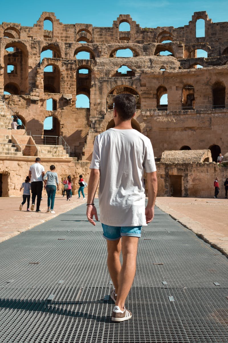 Man walking through the historic El Jem amphitheatre in Tunisia, a popular tourist attraction.