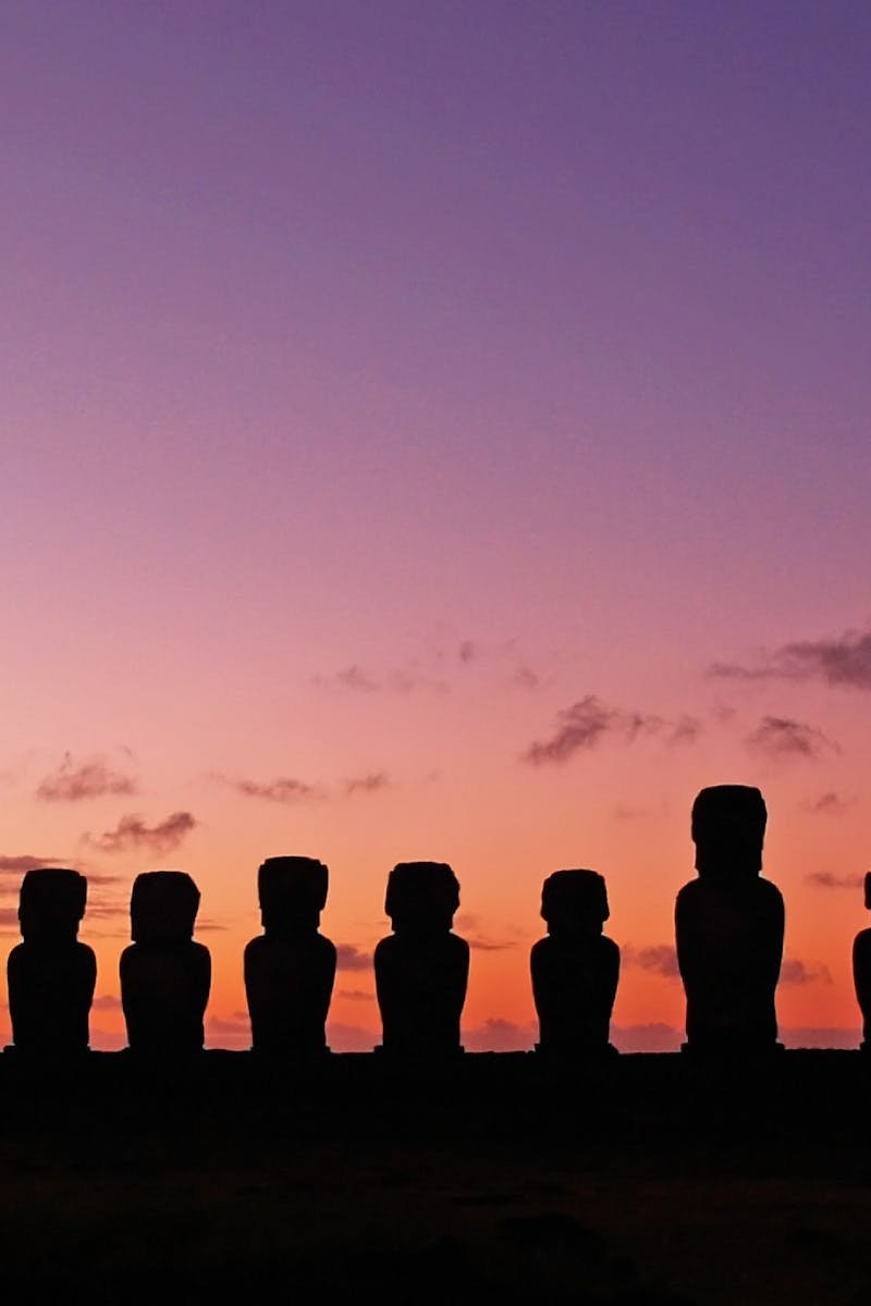 Panoramic view of Easter Island Moai statues silhouetted against a vibrant twilight sky.