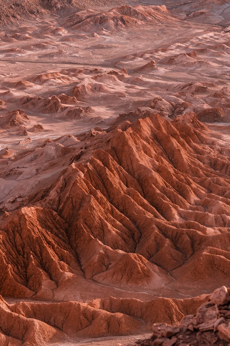 Explore the intricate patterns of desert dunes and mountains in this breathtaking aerial shot.