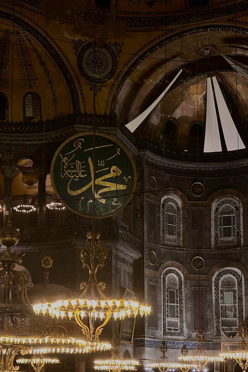 Historic interior of Hagia Sophia, showcasing Islamic calligraphy and grand chandeliers.