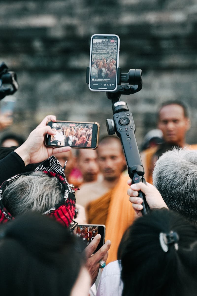 A crowd uses smartphones to capture a Buddhist ceremony at a historic site.