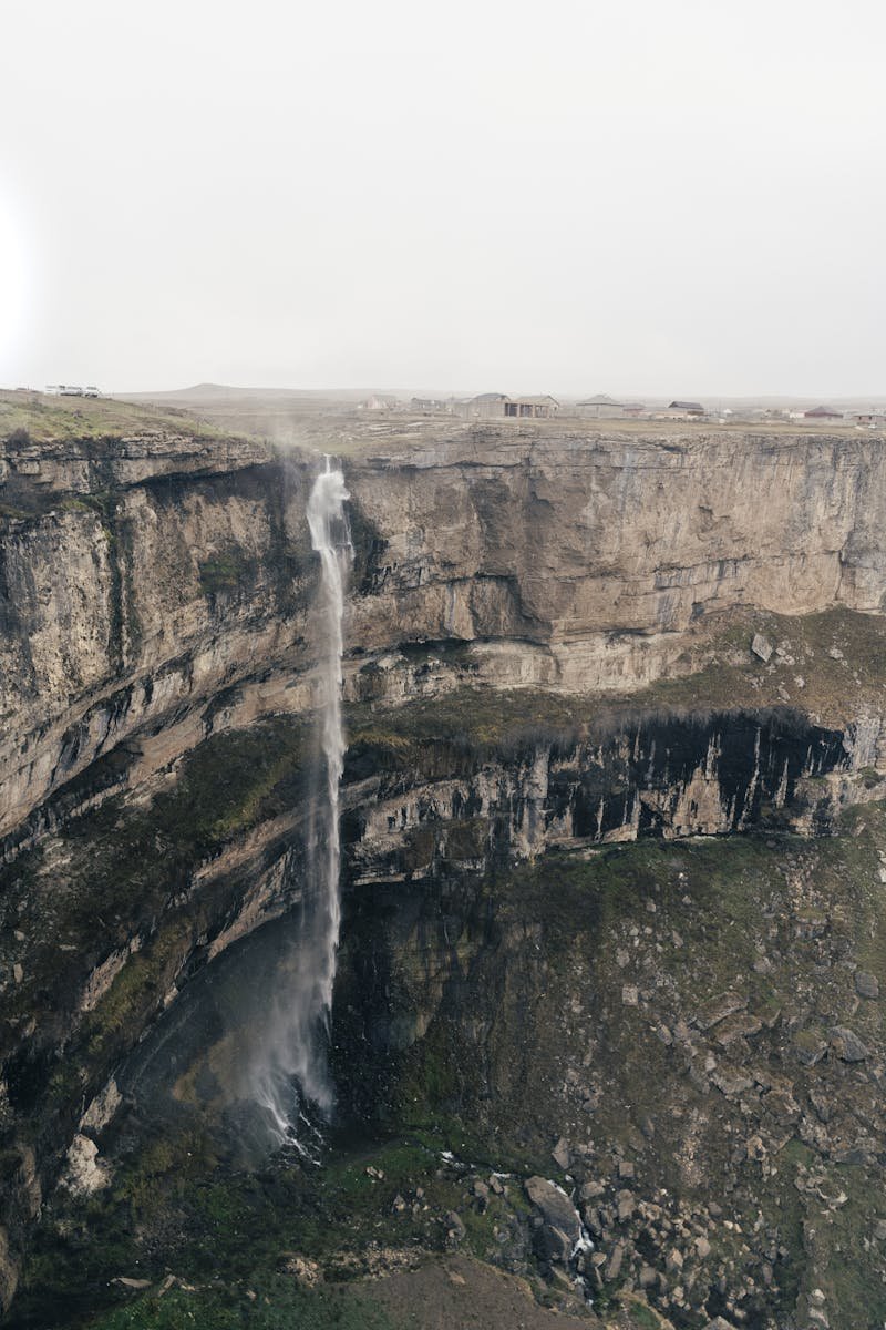A breathtaking view of a waterfall cascading down a rocky cliff in a remote mountainous landscape.