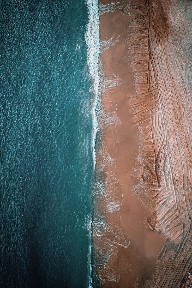 Stunning aerial shot of Byblos beach with turquoise waves and brown sand.