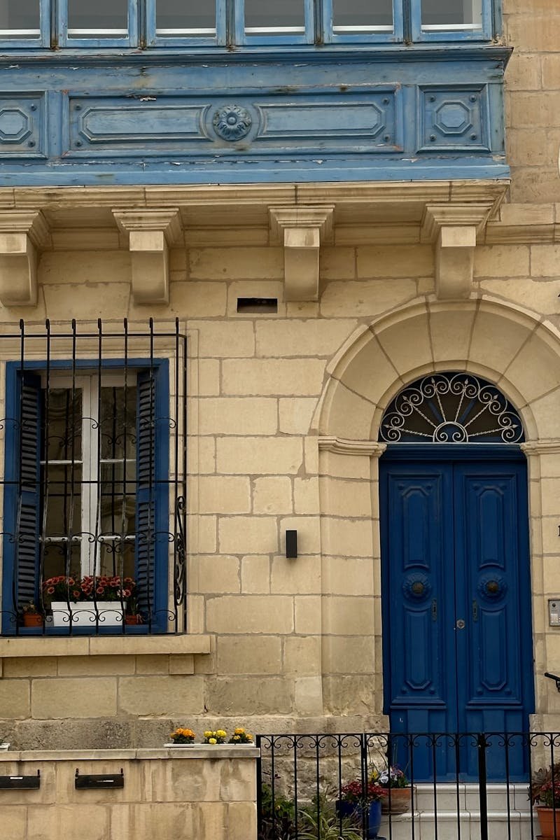 Charming Maltese architectural facade with traditional blue balcony and door in Mdina.