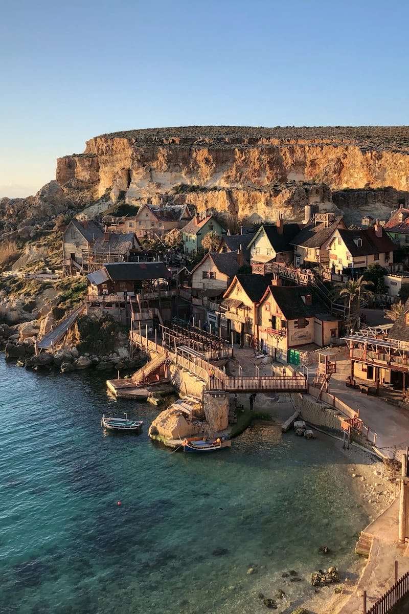 Picturesque cliffside view of Popeye Village in Il-Mellieħa, Malta with clear blue waters.