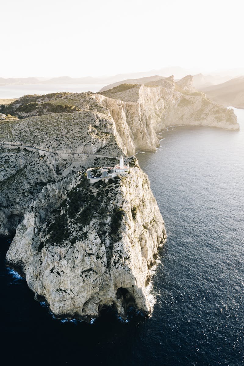 Breathtaking drone shot of rocky cliffs and tranquil sea at sunrise in Spain.