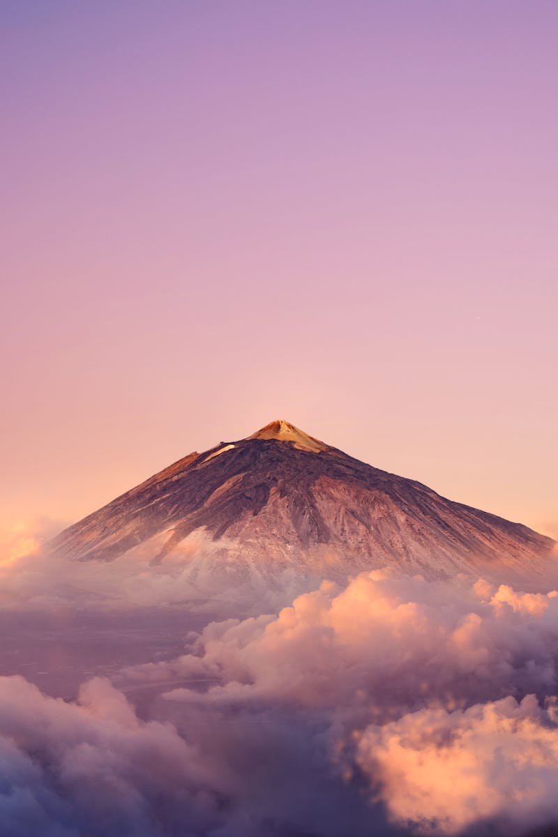 Stunning view of Mount Teide at sunrise surrounded by vibrant clouds and serene sky.