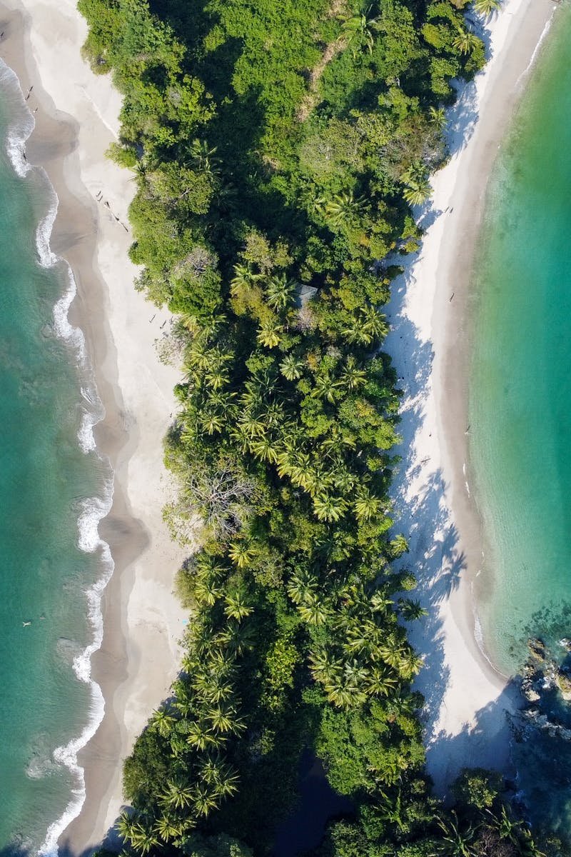 Stunning aerial view of Manuel Antonio Beach with lush green forest and turquoise ocean waters in Costa Rica.