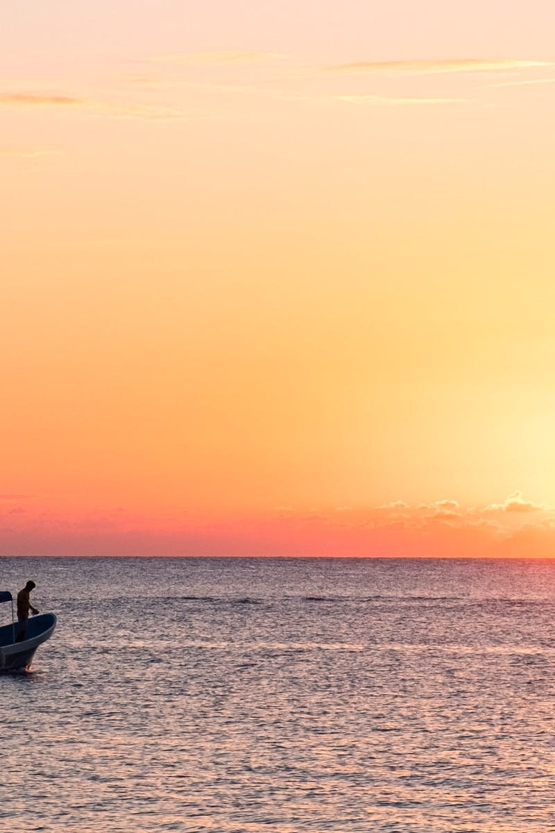 A serene scene of a boat on the ocean during sunset in West End, Bay Islands, Honduras.