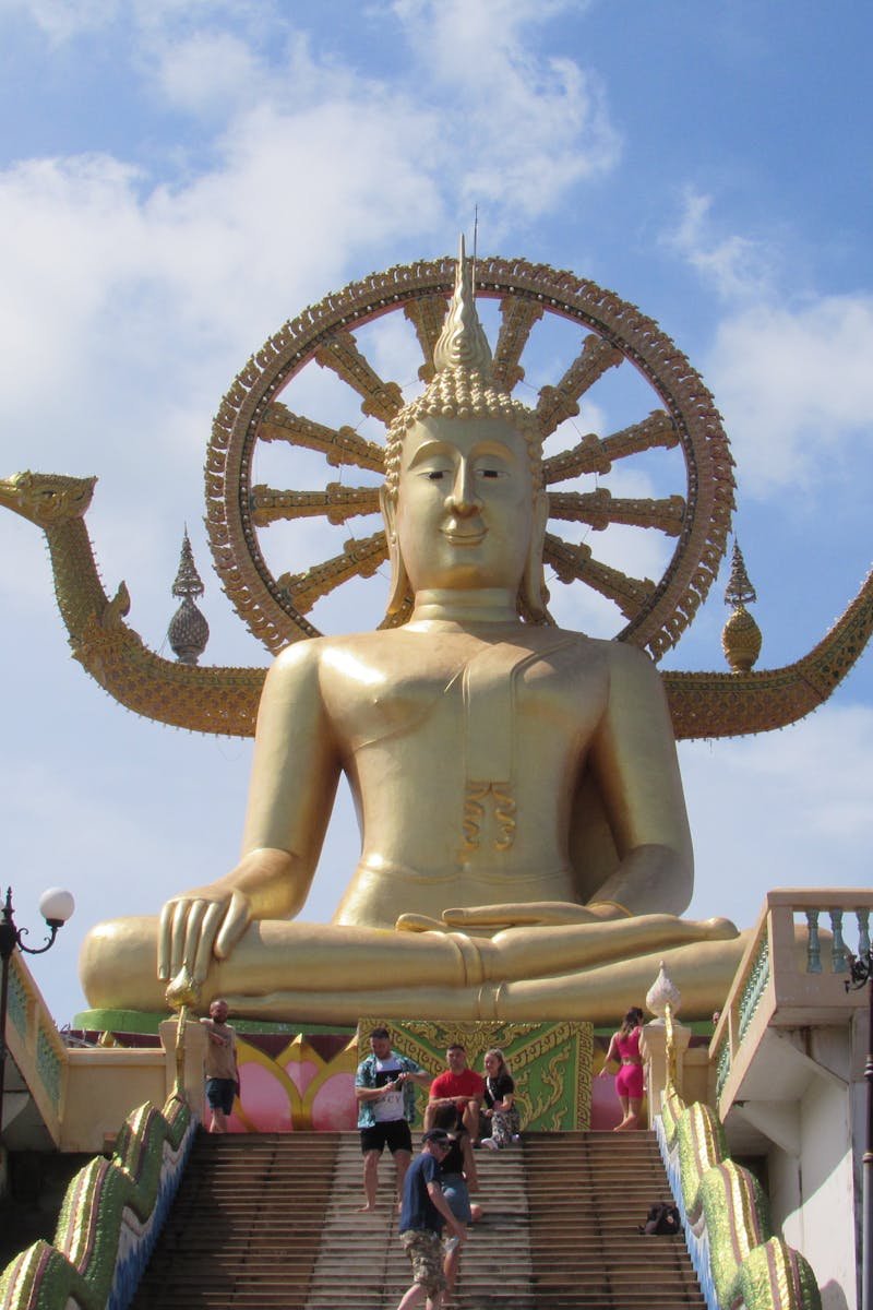 Majestic golden Buddha statue at Wat Phra Yai temple, Thailand, showcasing vibrant cultural architecture.