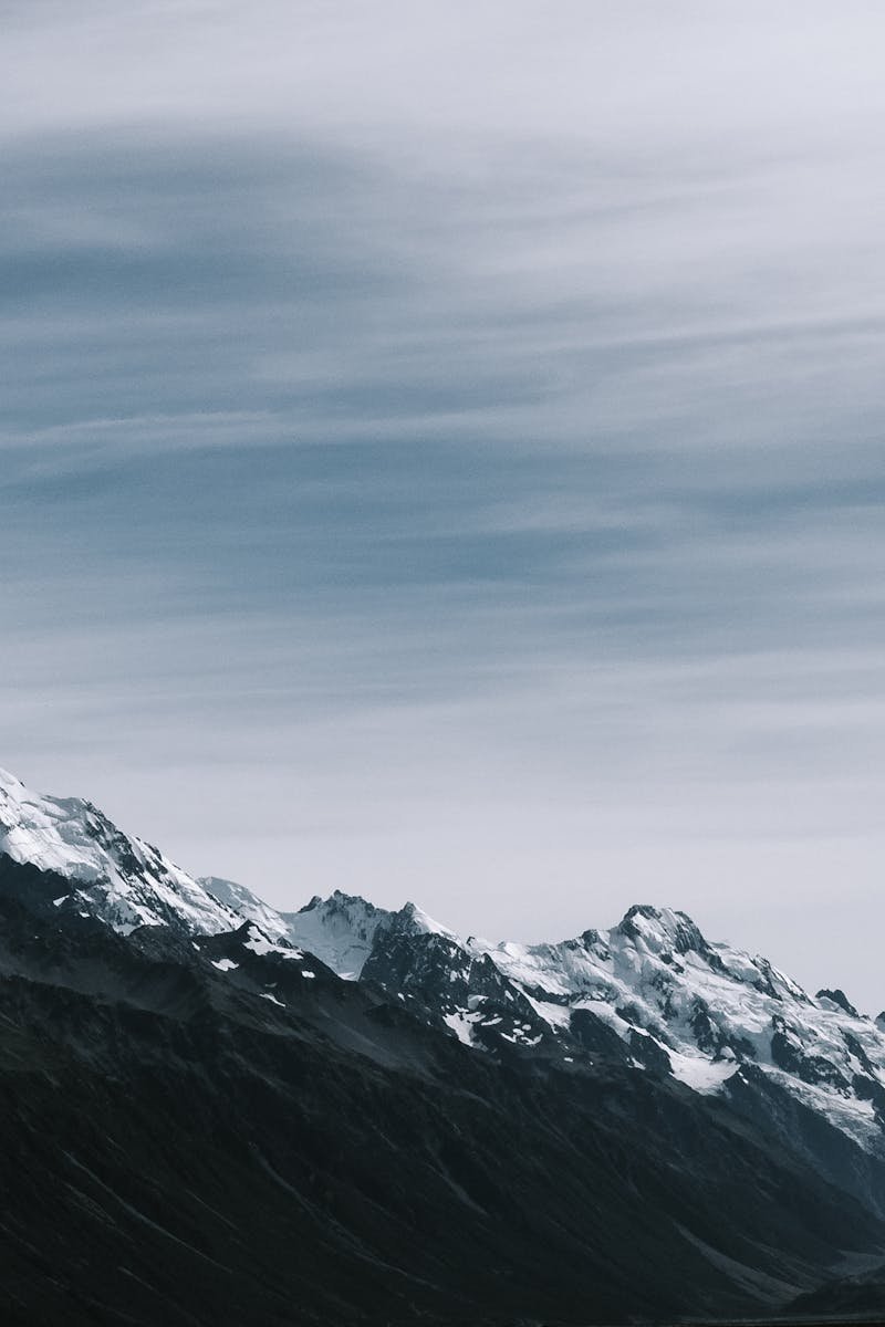 Breathtaking view of snow-capped mountain peaks under a cloudy sky.