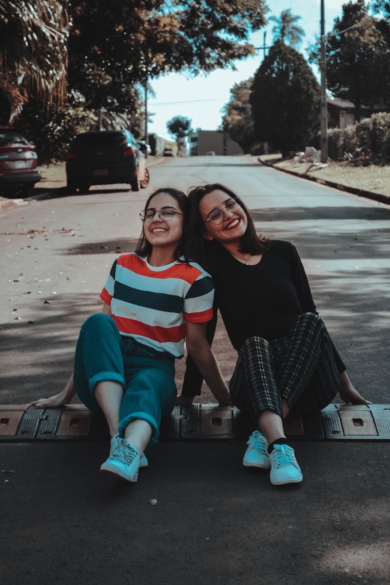 Two young women sitting on a sunny street in Ciudad del Este, enjoying friendship and laughter.