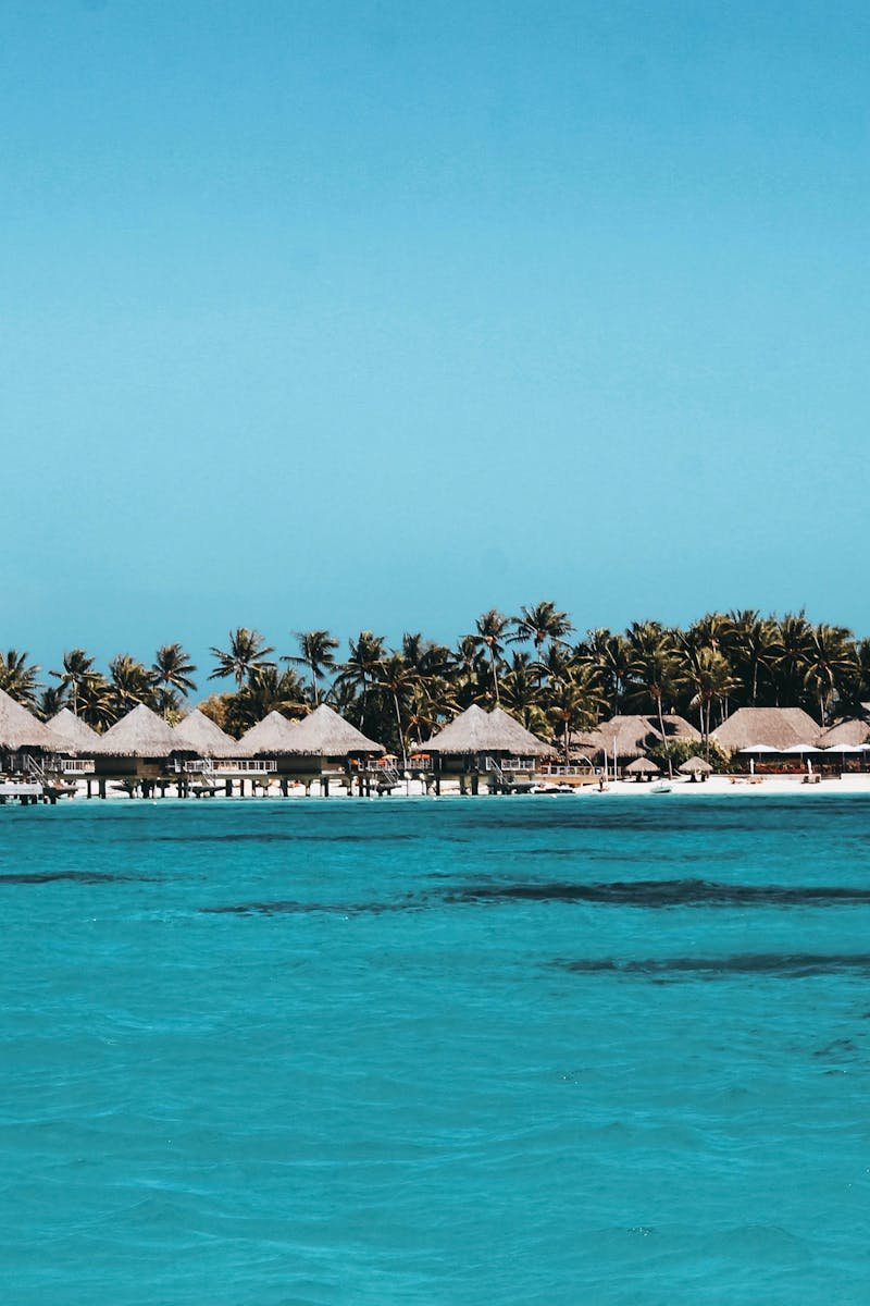 Idyllic bungalows line the turquoise waters of Vaitāpē, French Polynesia, showcasing a serene tropical paradise.