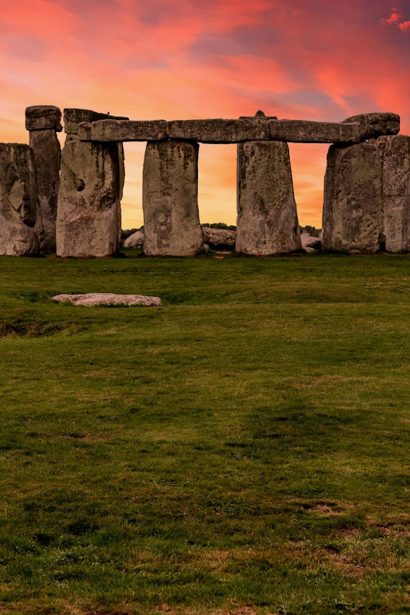 Capture of the iconic Stonehenge during a vibrant sunset with a dramatic sky.