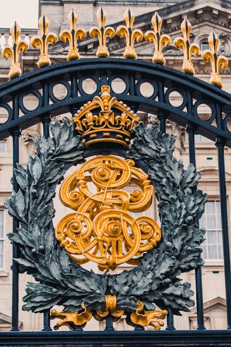 Detailed view of the ornate gold and black iron gate at Buckingham Palace, London.