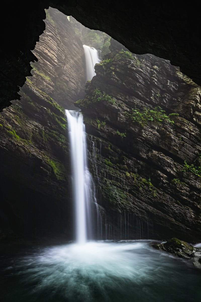Stunning view of a waterfall cascading within a cave surrounded by lush greenery, captured outdoors.