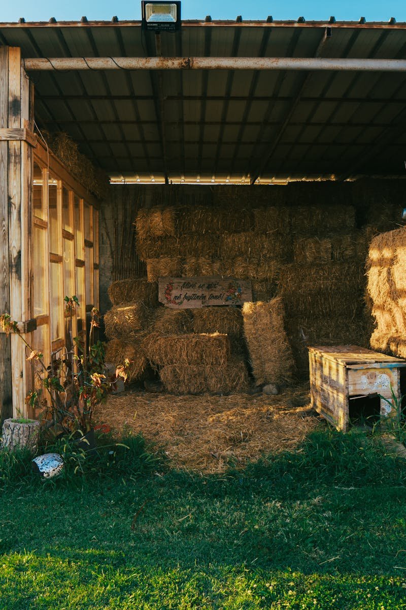 A charming rustic barn with hay bales in the countryside of Fishtë, Albania at sunset.