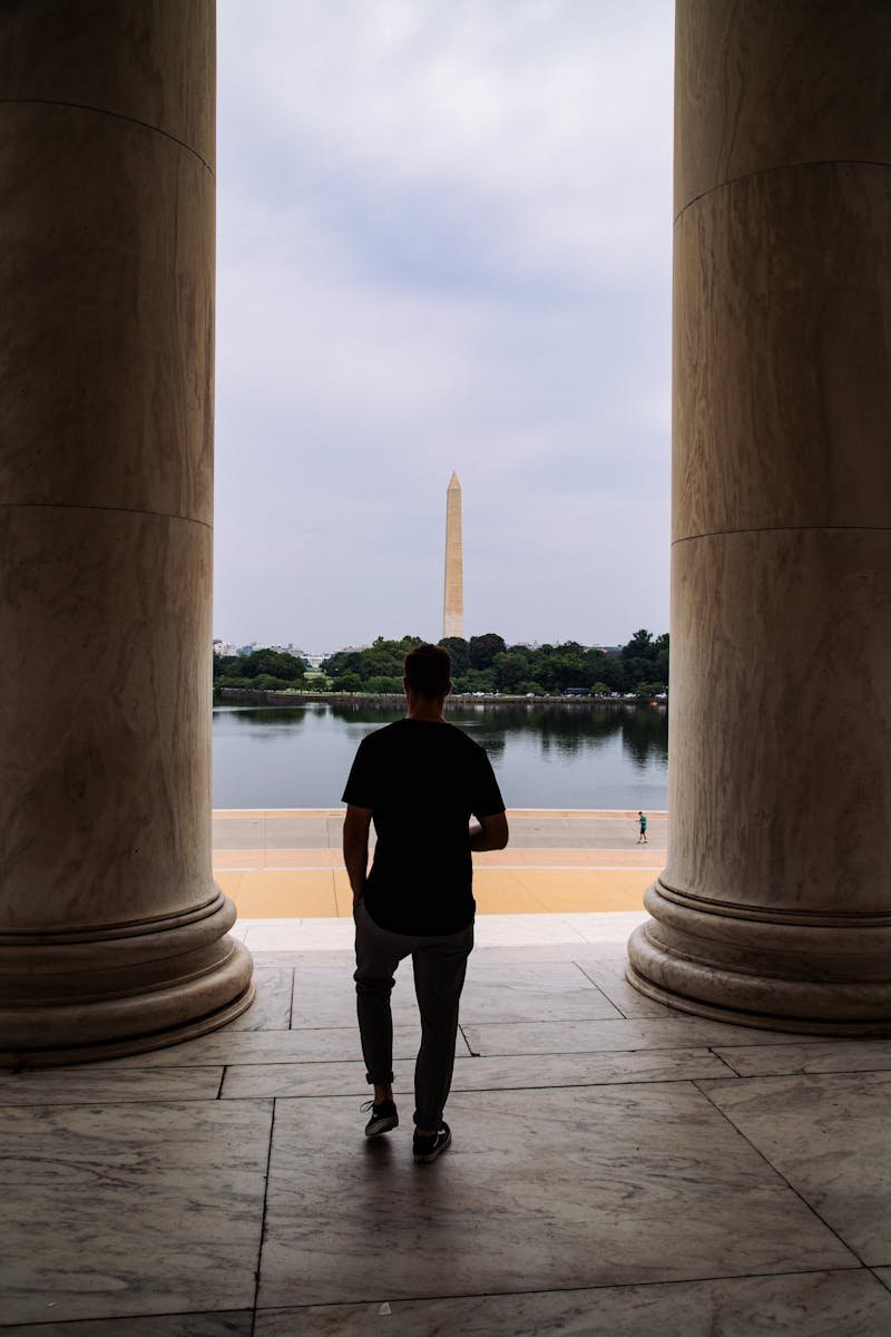 Silhouette of a person in the Jefferson Memorial, facing the Washington Monument across the Reflecting Pool.