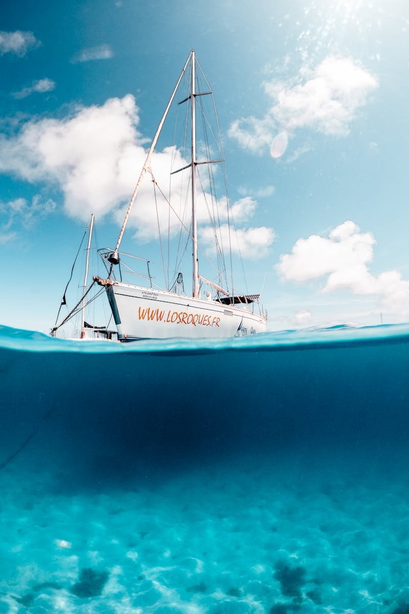 Scenic view of a sailboat over clear turquoise waters in Los Roques, under a bright sky.