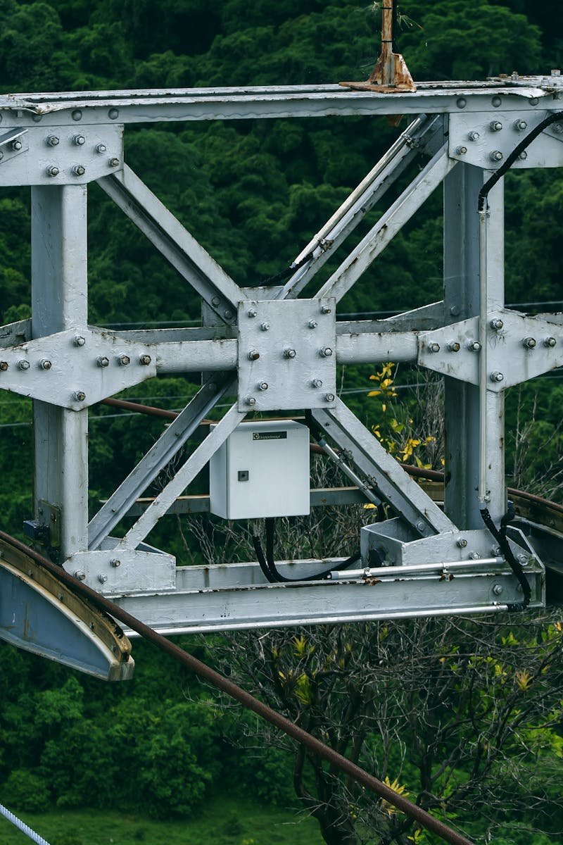 Detailed metalwork of Mérida cable car system amidst lush greenery.
