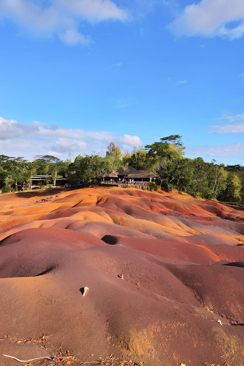 Vibrant seven-colored sand dunes under a clear sky in Chamarel, Mauritius, showcasing nature's artistry.